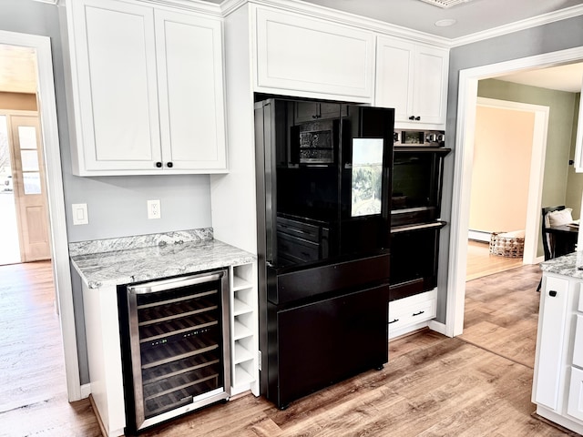 kitchen featuring light stone countertops, wine cooler, light wood-style flooring, white cabinets, and black appliances