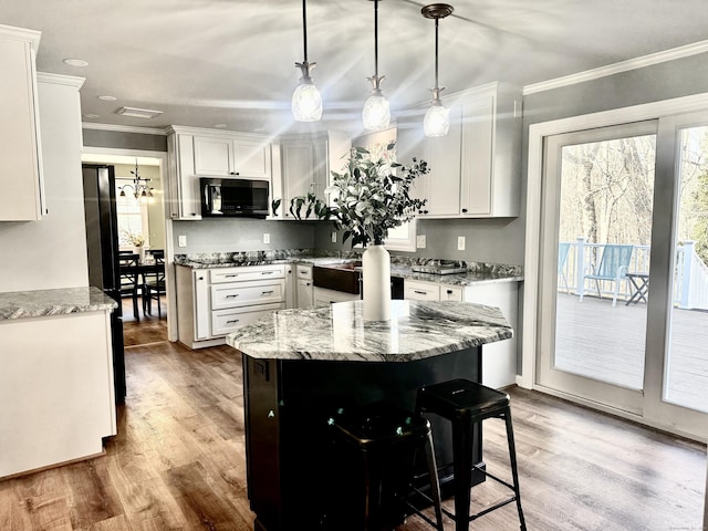 kitchen featuring black appliances, white cabinets, light wood-type flooring, and ornamental molding