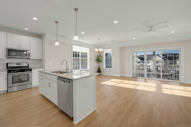 kitchen with stainless steel appliances, light wood-type flooring, white cabinetry, and ornamental molding