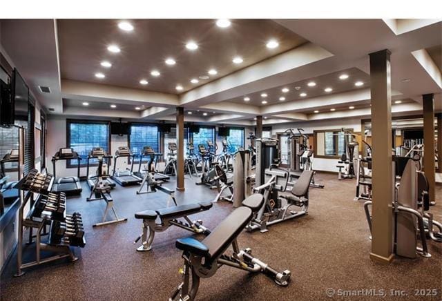 exercise room with a tray ceiling, visible vents, and recessed lighting