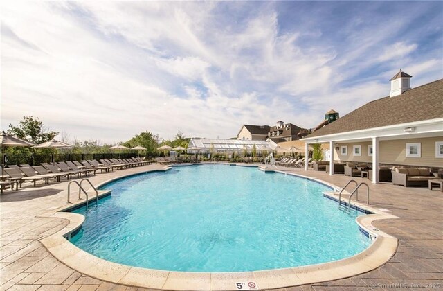 community pool with a patio, an outdoor living space, and fence