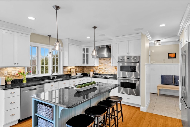 kitchen featuring stainless steel appliances, white cabinets, a sink, and wall chimney exhaust hood