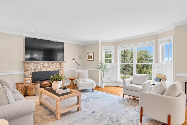 living room featuring a healthy amount of sunlight, a fireplace, ornamental molding, and wood finished floors