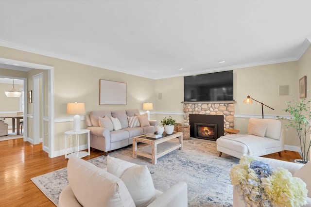 living room featuring ornamental molding, a stone fireplace, wood finished floors, and baseboards