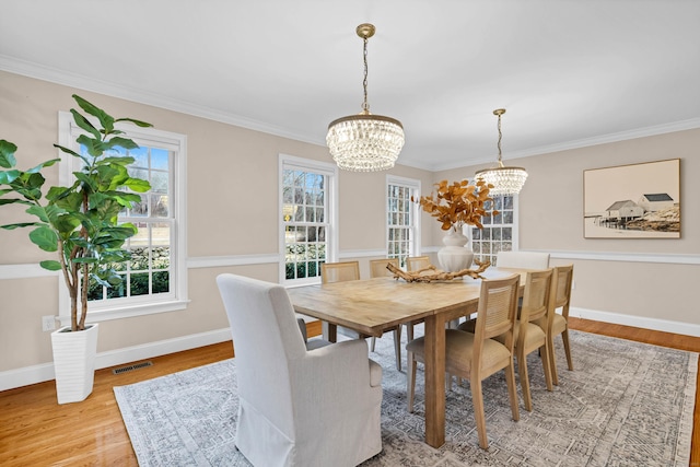 dining room with a chandelier, light wood-style flooring, visible vents, baseboards, and crown molding