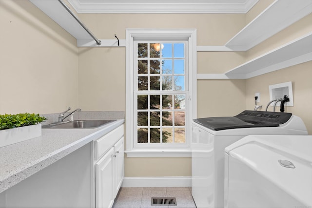 washroom with a sink, visible vents, cabinet space, washer and clothes dryer, and crown molding