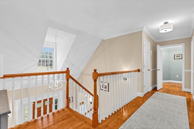 hall featuring ornamental molding, a chandelier, baseboards, and wood finished floors