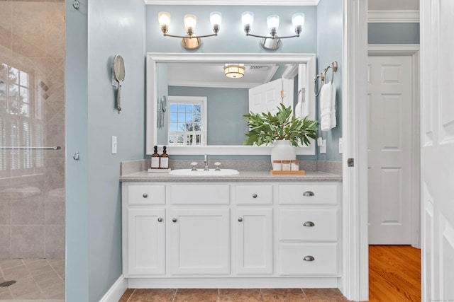 full bath featuring baseboards, a tile shower, crown molding, and vanity