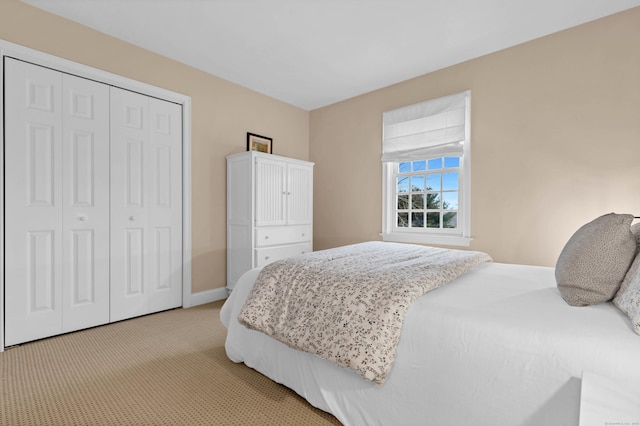 bedroom with baseboards, a closet, and light colored carpet