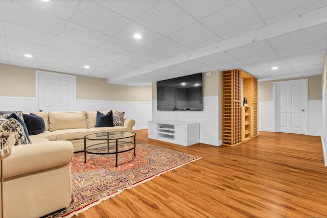 living room with recessed lighting, a wainscoted wall, a drop ceiling, and wood finished floors