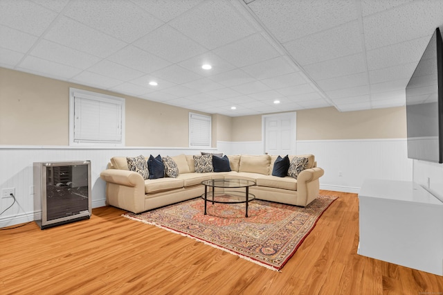 living room with light wood-type flooring, beverage cooler, recessed lighting, and wainscoting