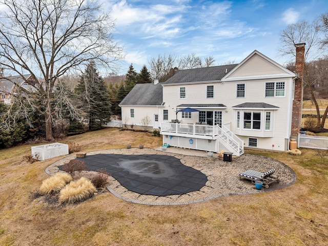 rear view of house with a patio, a chimney, fence, driveway, and a wooden deck