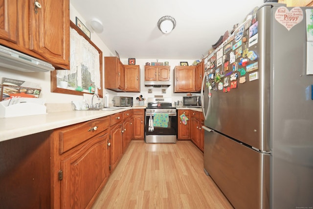 kitchen featuring brown cabinetry, stainless steel appliances, light wood-type flooring, and light countertops