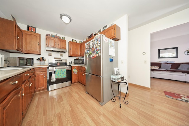 kitchen featuring light countertops, appliances with stainless steel finishes, light wood-style floors, brown cabinetry, and a sink