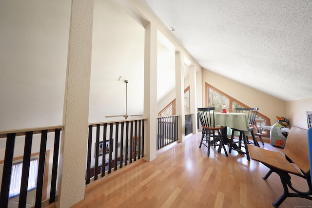 dining room with ceiling fan, lofted ceiling, a textured ceiling, and wood finished floors