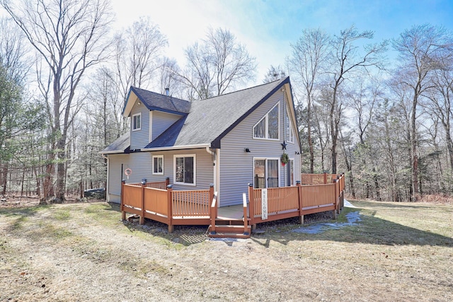 exterior space featuring a deck, a lawn, and roof with shingles