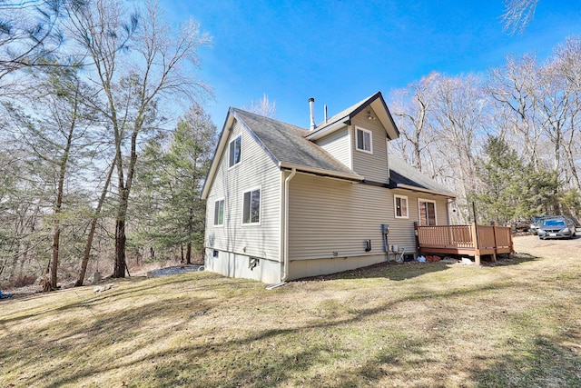 view of home's exterior featuring a deck, a lawn, and roof with shingles