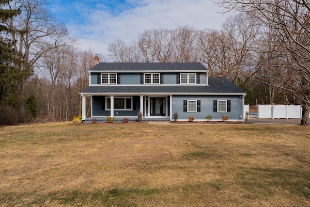 view of front of home with a porch, a chimney, a front lawn, and a shingled roof