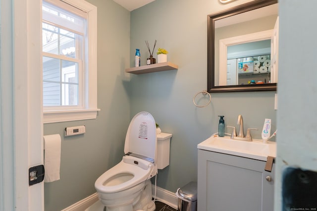 half bathroom featuring vanity, toilet, and baseboards