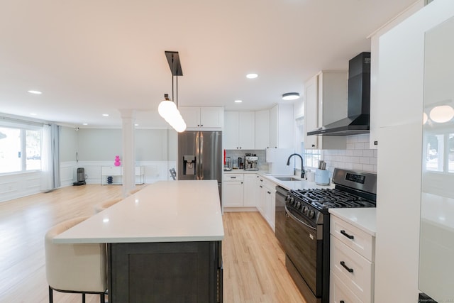 kitchen with a sink, stainless steel appliances, wall chimney range hood, tasteful backsplash, and a center island