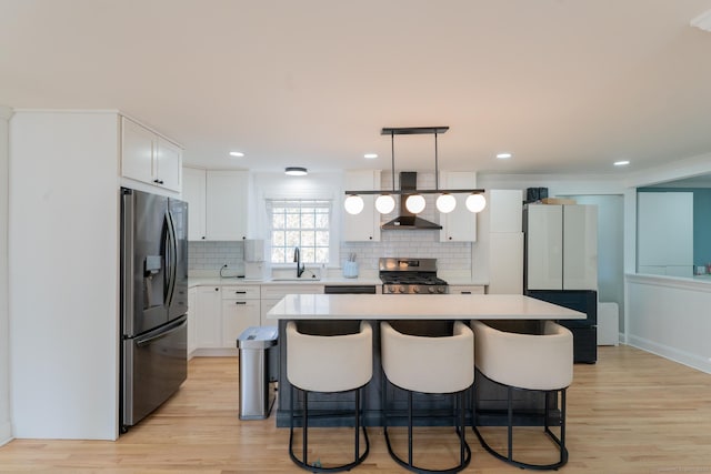 kitchen featuring a breakfast bar, a sink, tasteful backsplash, appliances with stainless steel finishes, and light countertops