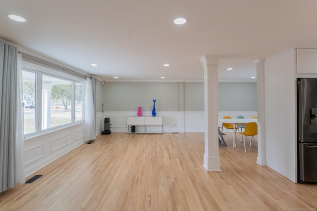 interior space with light wood-type flooring, a wainscoted wall, recessed lighting, a decorative wall, and ornate columns