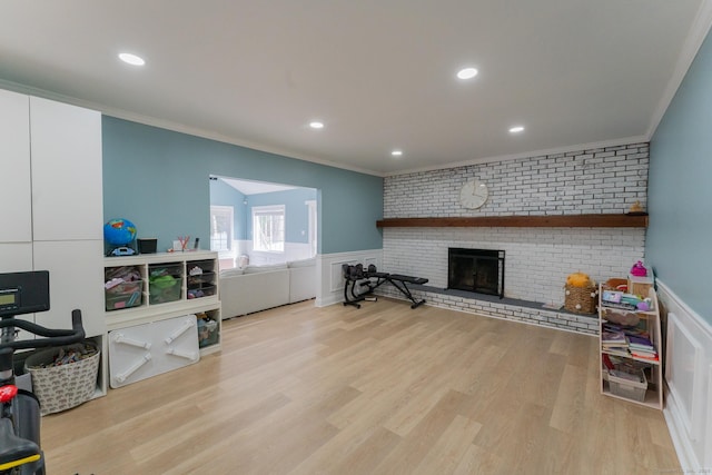 living room with a fireplace, wood finished floors, wainscoting, and ornamental molding