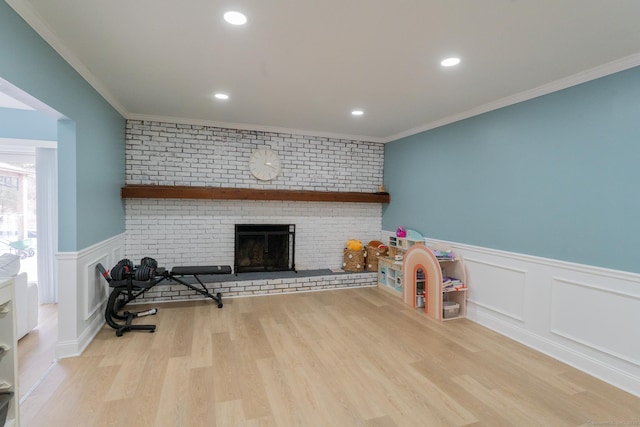 interior space featuring a brick fireplace, wood finished floors, wainscoting, and ornamental molding