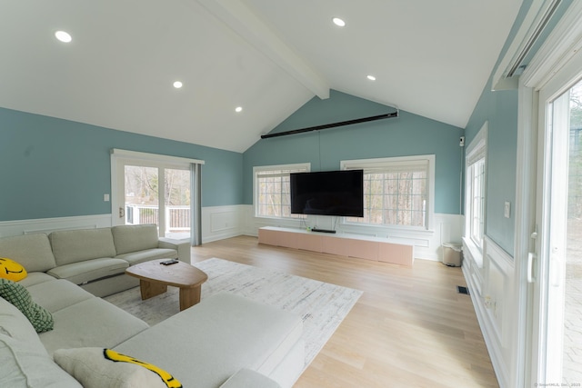 living room with lofted ceiling with beams, visible vents, wainscoting, and light wood finished floors