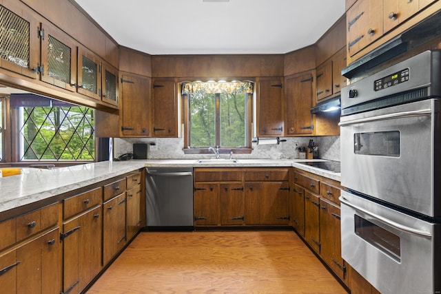 4 Wildwood Ln, Weston, CT 06883 - kitchen featuring stainless steel appliances, decorative backsplash, a sink, glass insert cabinets, and light wood-style floors