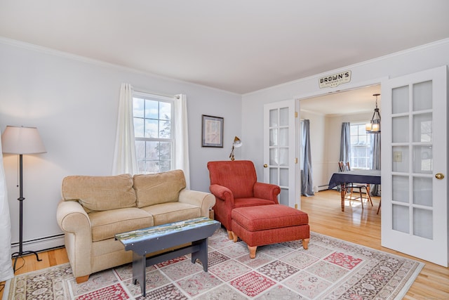 living room with light wood finished floors, crown molding, baseboard heating, french doors, and a baseboard radiator