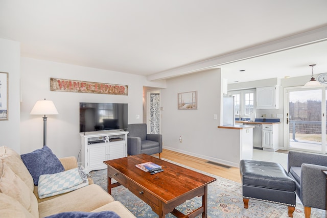 living area featuring visible vents, light wood-type flooring, and baseboards