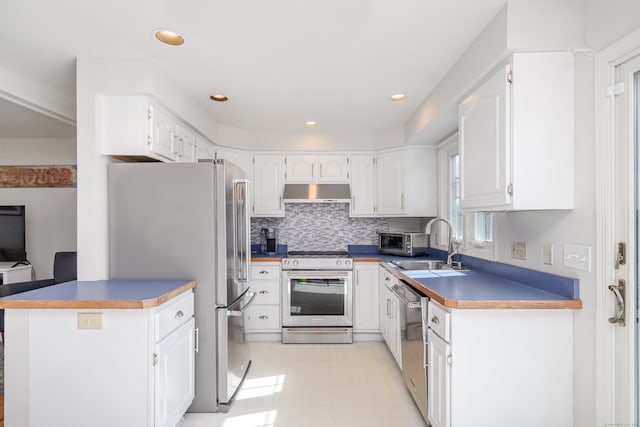 kitchen with under cabinet range hood, light floors, appliances with stainless steel finishes, and white cabinetry