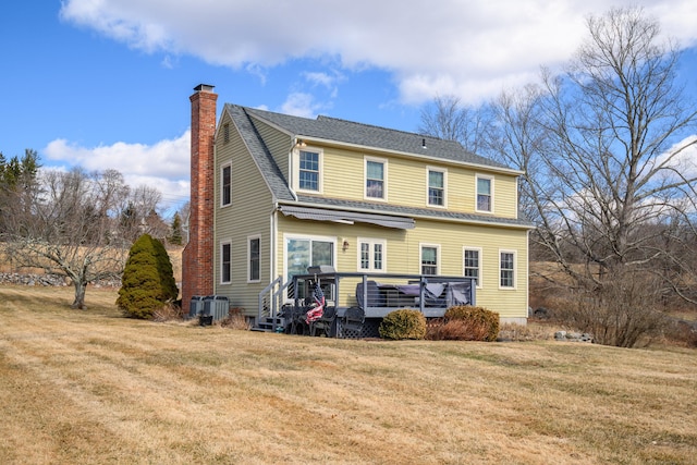 rear view of property featuring a yard, roof with shingles, a deck, and a chimney