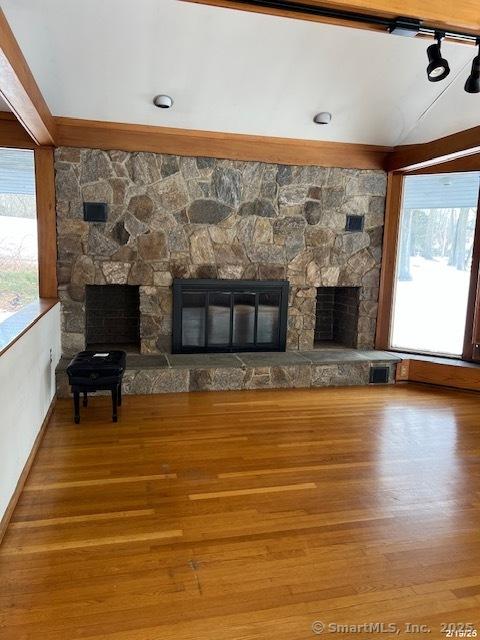 unfurnished living room featuring visible vents, a stone fireplace, and wood finished floors