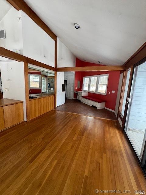 unfurnished living room with dark wood-style floors, visible vents, and high vaulted ceiling