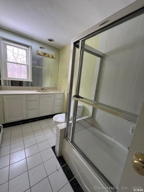 full bath with enclosed tub / shower combo, tile patterned flooring, and vanity