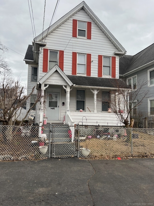 view of front facade with a fenced front yard, a gate, and a porch