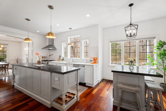 kitchen with plenty of natural light, wall chimney exhaust hood, stainless steel dishwasher, and decorative backsplash