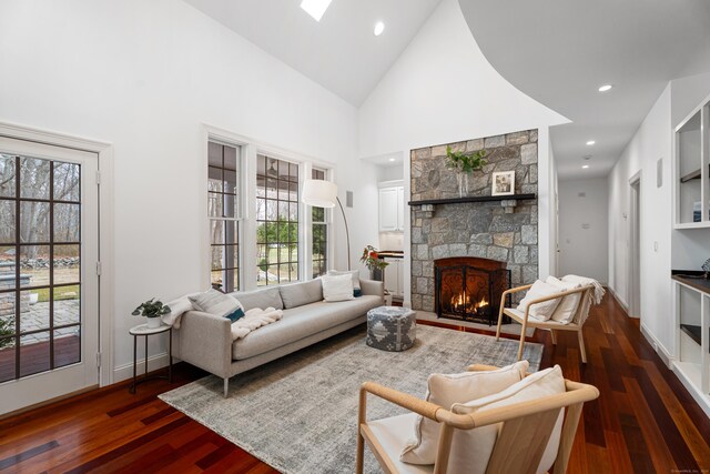 living room featuring high vaulted ceiling, a stone fireplace, dark wood finished floors, baseboards, and recessed lighting