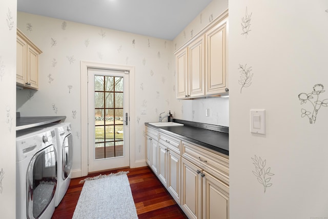 clothes washing area with dark wood-style floors, a sink, washing machine and dryer, baseboards, and cabinet space