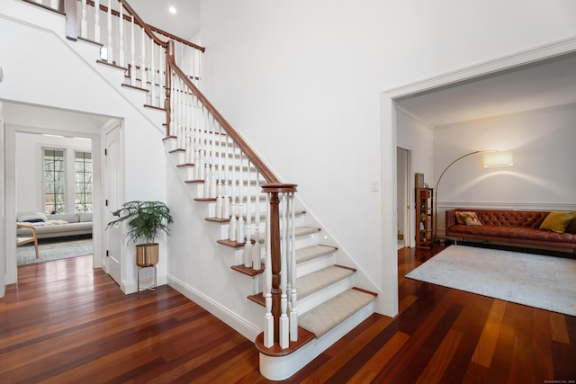 stairway featuring wood finished floors, baseboards, and ornamental molding