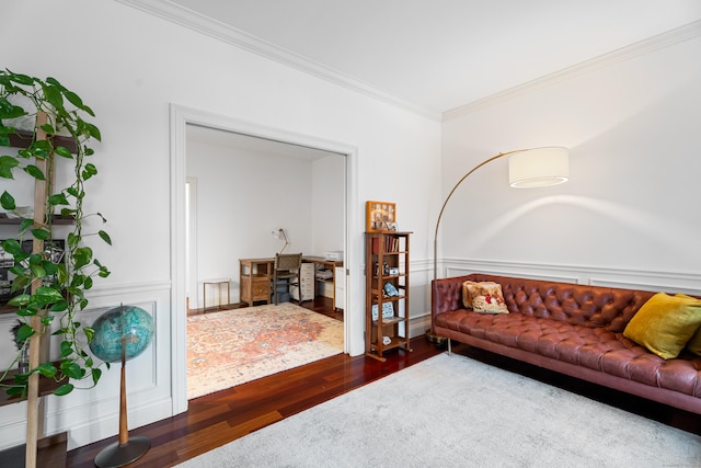 living area featuring wood finished floors, crown molding, and wainscoting