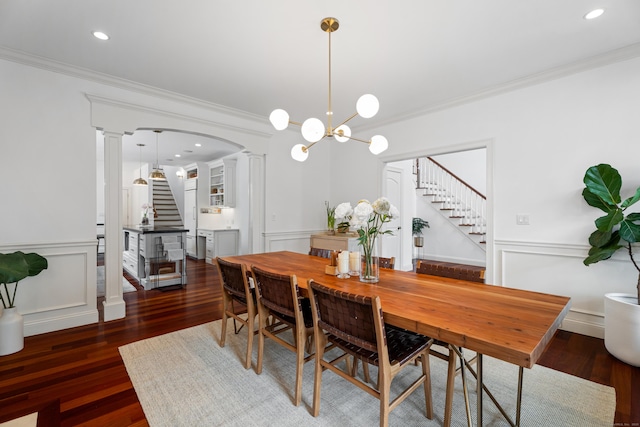 dining area featuring stairway, a wainscoted wall, ornamental molding, and decorative columns