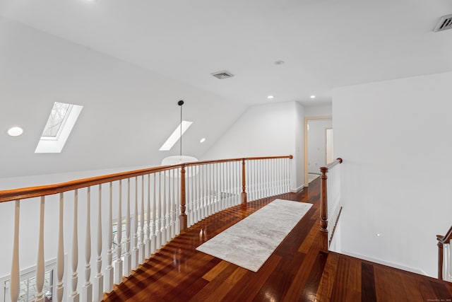 corridor with wood finished floors, visible vents, recessed lighting, and lofted ceiling with skylight