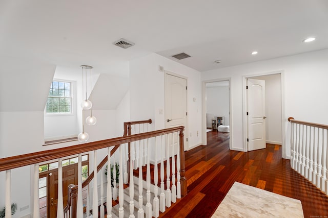 hall with wood finished floors, visible vents, recessed lighting, and an upstairs landing