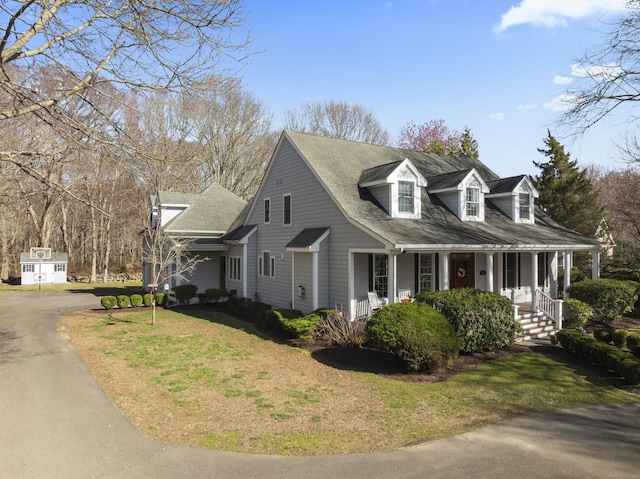 view of front facade featuring aphalt driveway, a porch, roof with shingles, and a front yard