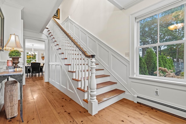 1 Hathaway Rd, East Lyme, CT 06333 - stairway featuring a baseboard heating unit, a decorative wall, wood-type flooring, a chandelier, and healthy amount of natural light