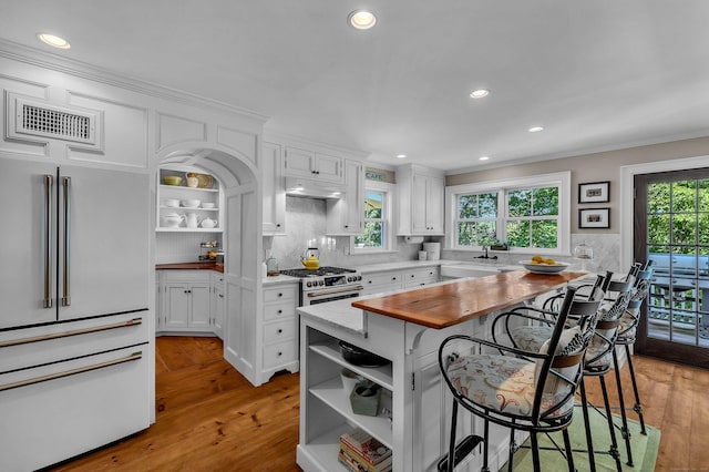 1 Hathaway Rd, East Lyme, CT 06333 - kitchen featuring premium appliances, open shelves, light wood-type flooring, white cabinetry, and a breakfast bar area