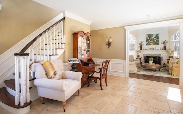 sitting room featuring crown molding, stone tile floors, stairway, and a premium fireplace